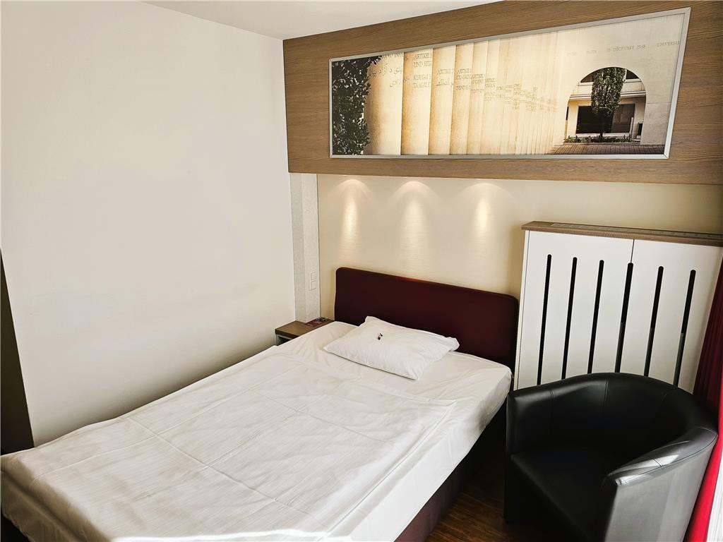 Standard single room with queen-size bed, desk, spacious wardrobe, wall mirror, seating area, TV, bathroom