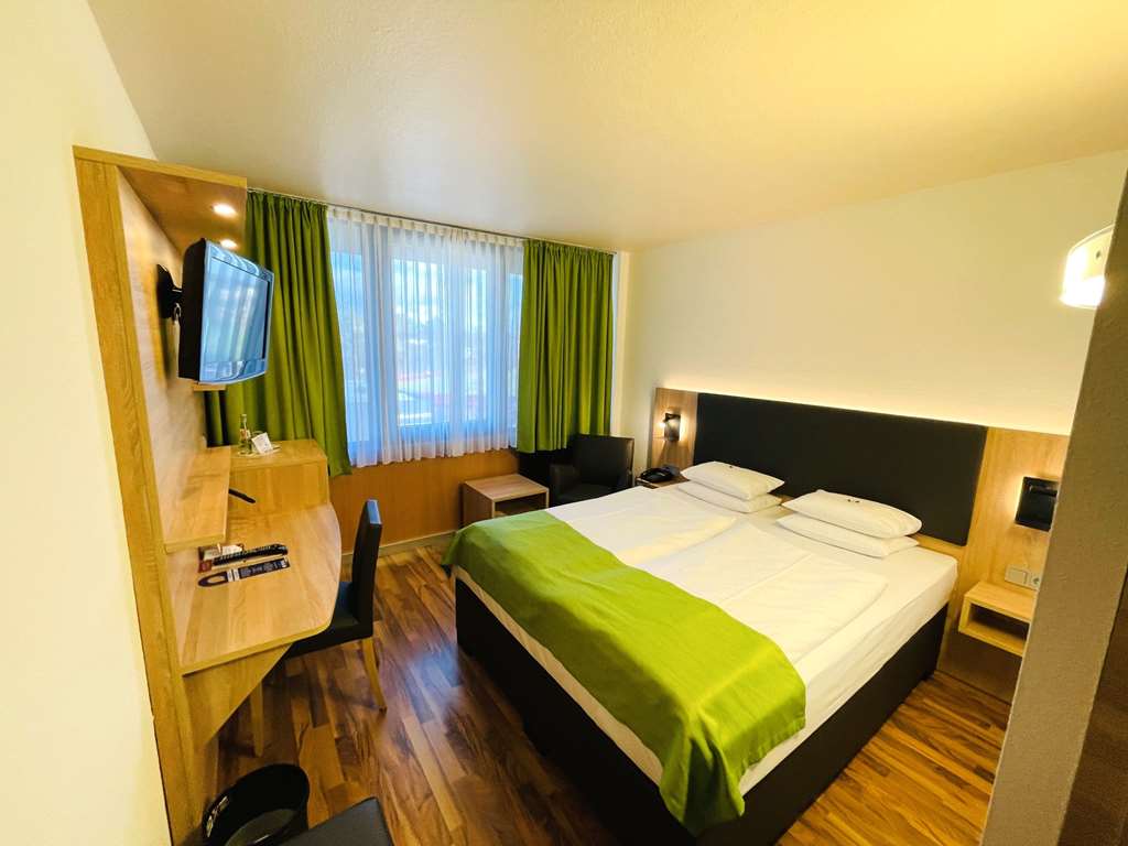 Comfort double room with queen-size bed, desk, spacious wardrobe, wall mirror, seating, TV, bathroom