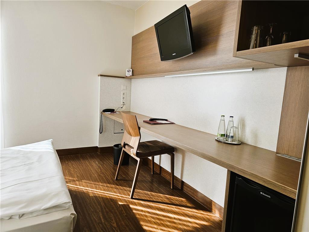 Standard single room with queen-size bed, desk, spacious wardrobe, wall mirror, seating area, TV, bathroom