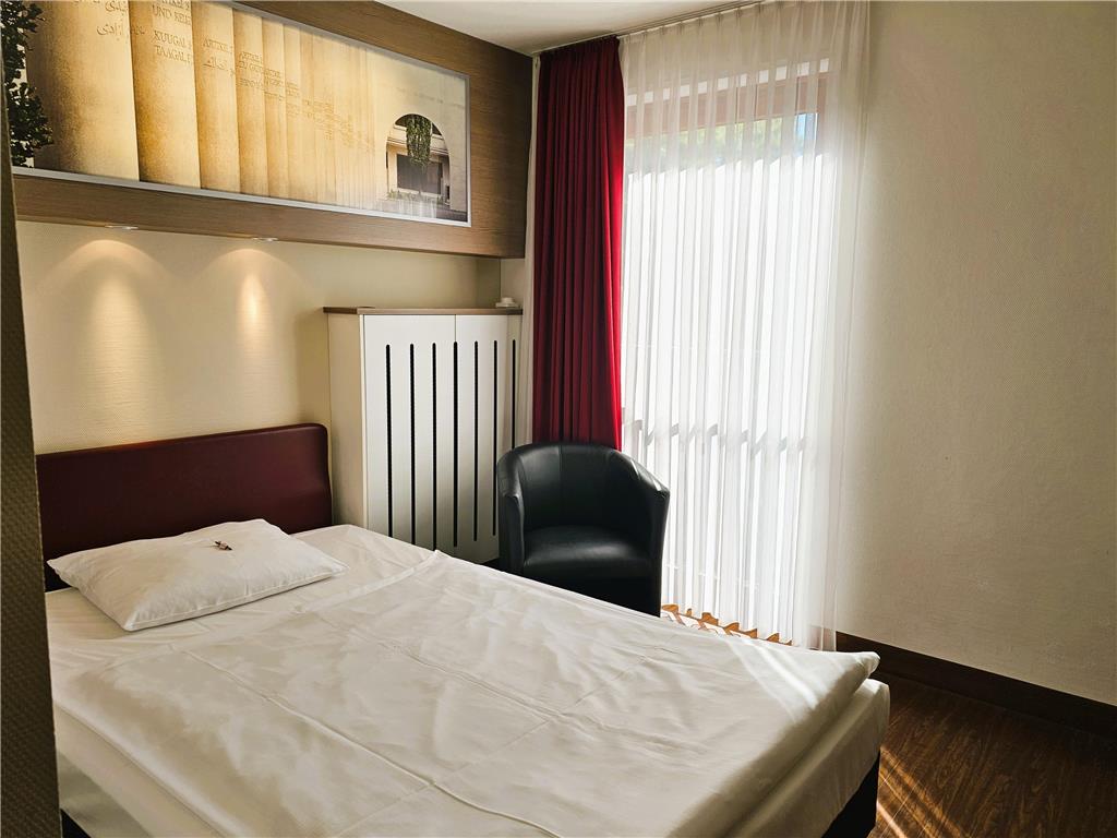 Standard single room with queen-size bed, desk, spacious wardrobe, wall mirror, seating area, TV, bathroom