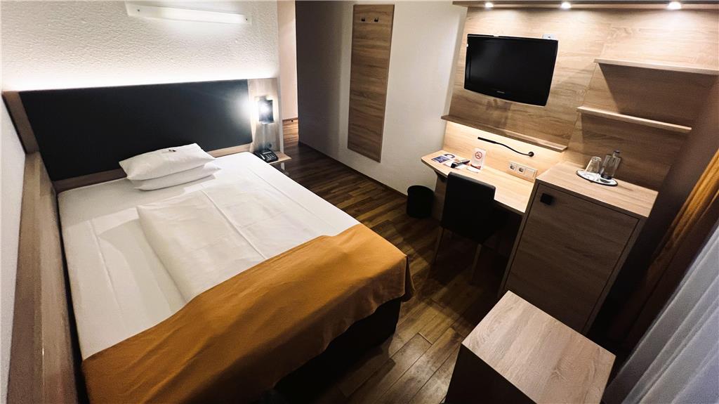 Comfort single room with single bed, desk, spacious wardrobe, wall mirror, seating, TV, bathroom
